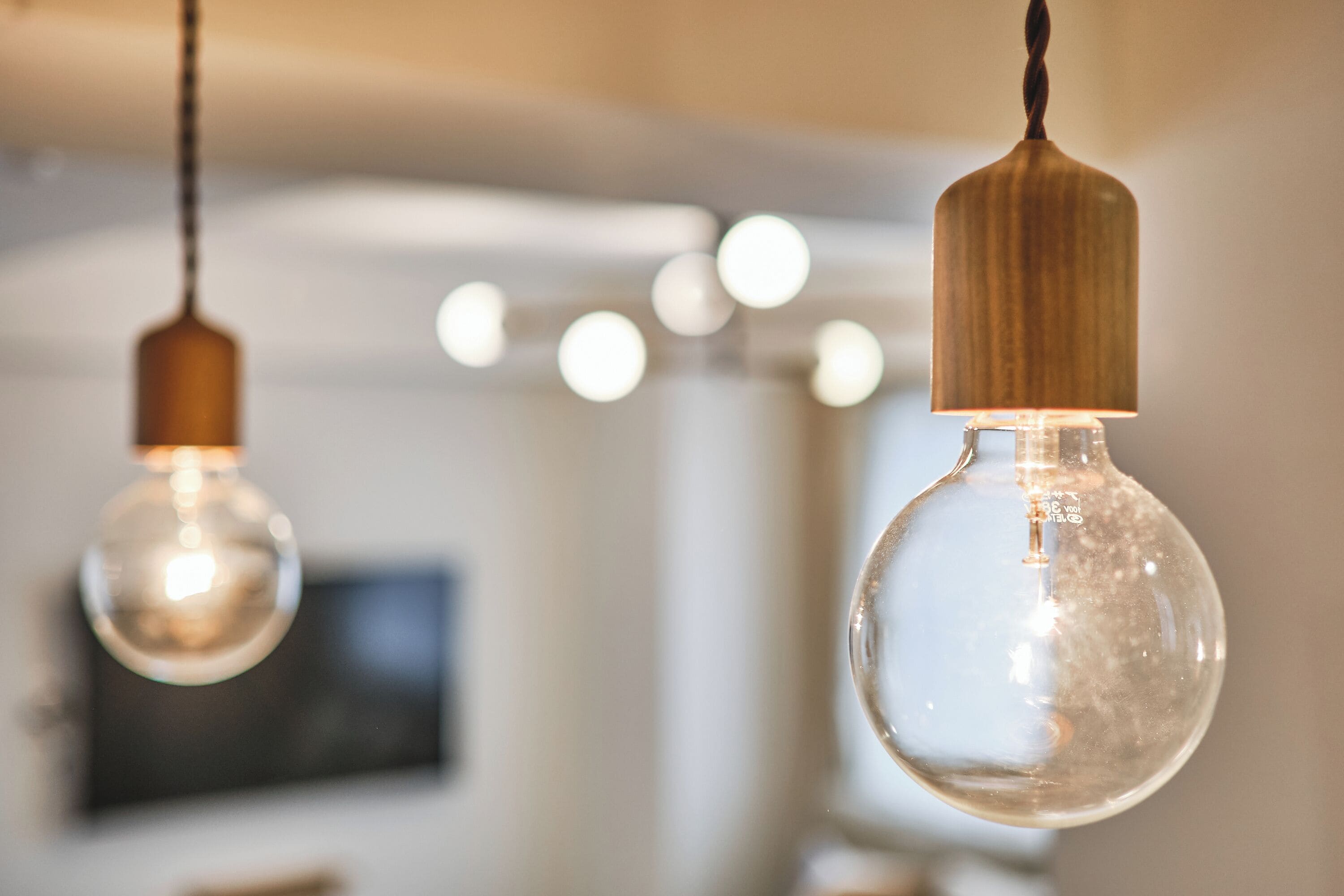 Two hanging light bulbs with wooden shades in a room.