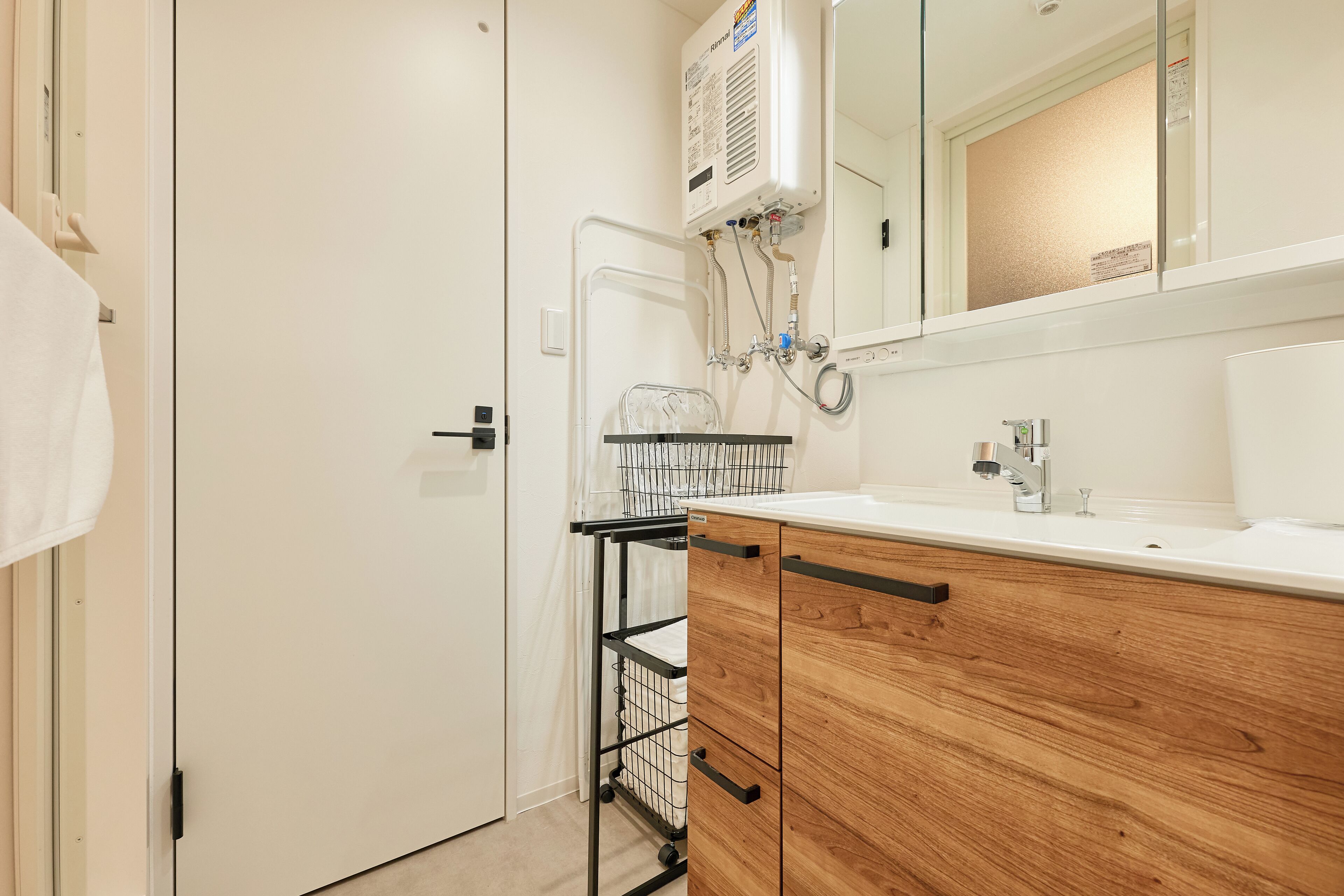 A bathroom with a white sink, wooden cabinets, a towel rack, and a mirror.