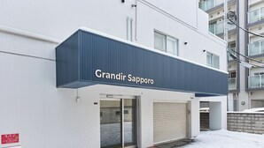 Un edificio con un letrero que dice "Grandir Sapporo" y una puerta de garaje cerrada.
