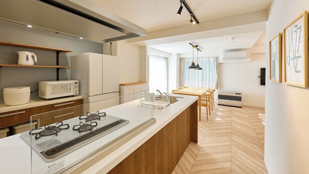 Una cocina moderna con una isla central, electrodomésticos integrados y un comedor con mesa y sillas de madera.