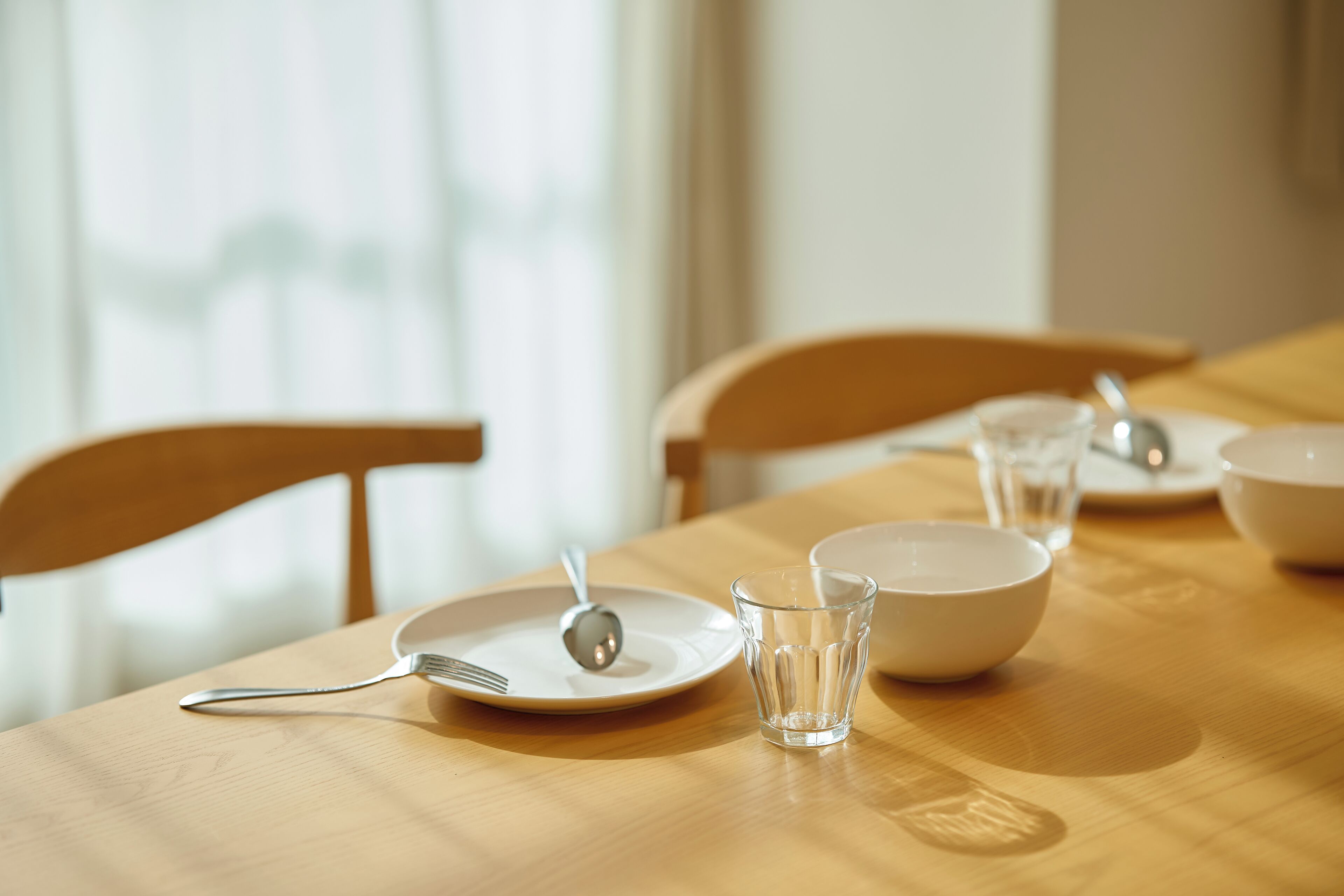 A dining table with plates, a glass, and cutlery.