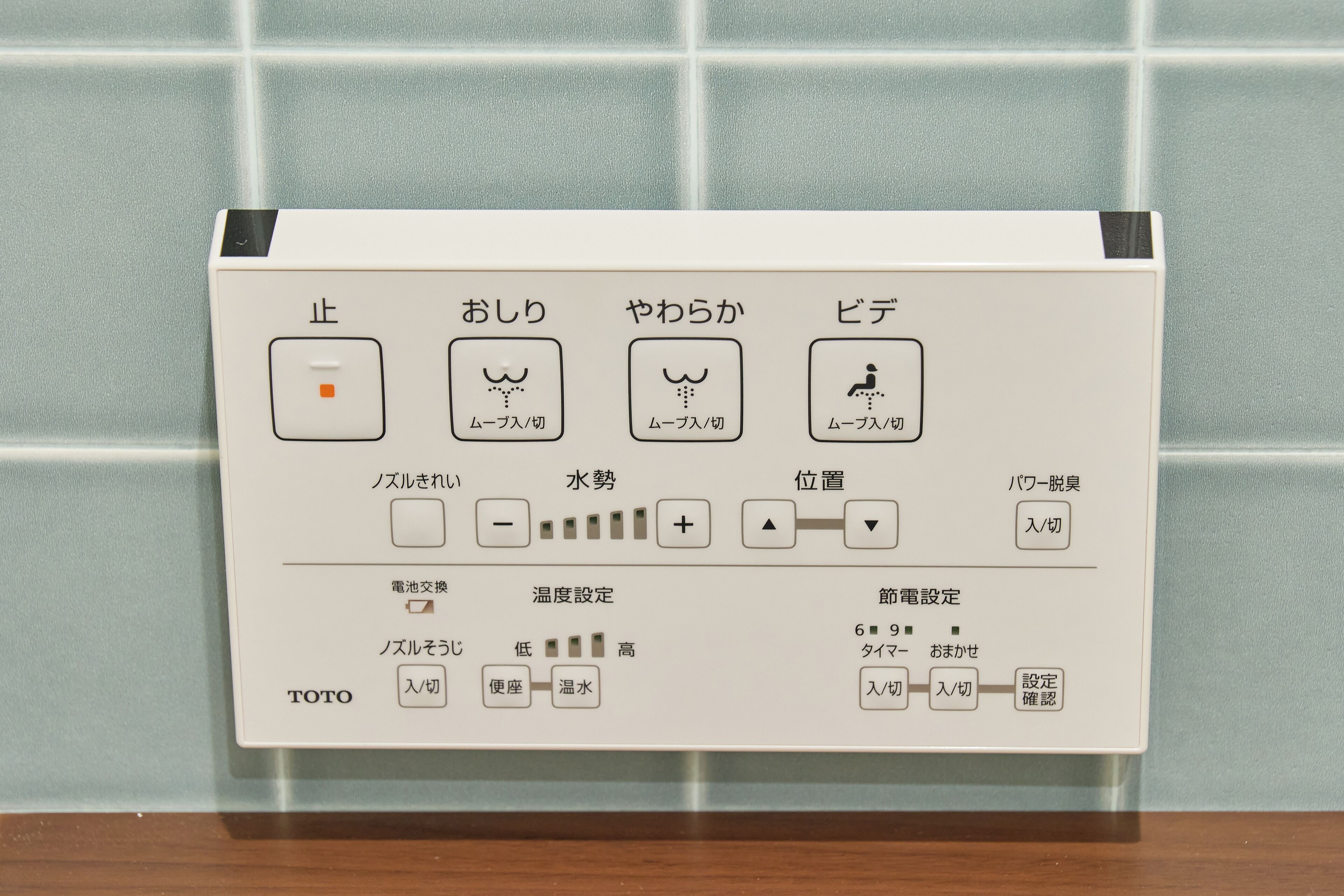 A control panel with Japanese labels for various functions, including a button with a square and a dot, a switch with a plus and minus, and a series of buttons with numbers and symbols.