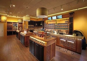 A spacious bar area with a central island, bar stools, and shelves stocked with beverages. - Spacious 2BD Riverfront Cabin| Hot Tub| Steam shower| Fast WiFi| Private Retreat (Ellijay)