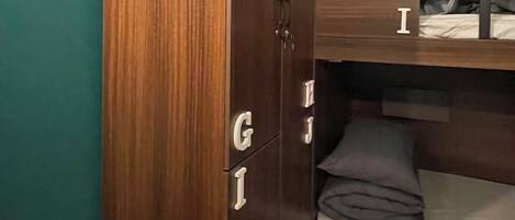 A compact room with a bunk bed, a wardrobe with drawers, and an air conditioning unit.