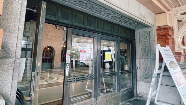 A building entrance with a stone facade, a glass door, and a sign indicating a pull mechanism. - Georgie Accommodation (Auckland)