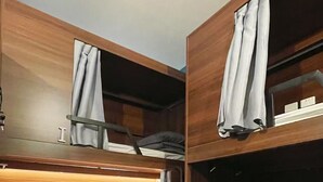 A bunk bed room with wooden headboards, a window with curtains, and a carpeted floor. - Georgie Accommodation (Auckland)
