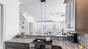 A modern kitchen with a black stove, a coffee maker, and a brick backsplash.