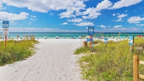 A beach path leading to the ocean with signs indicating amenities and access points.