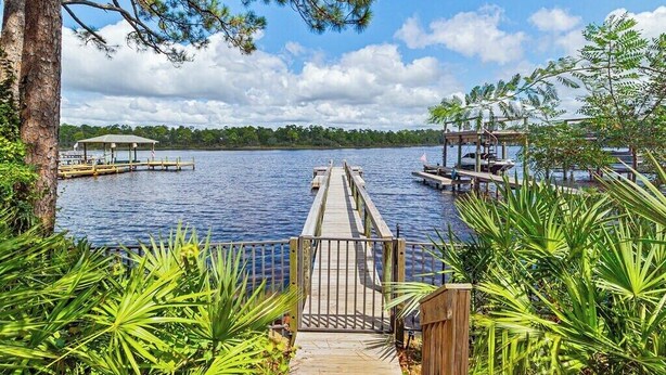 A wooden dock leading to a lake with a gazebo and a covered area.