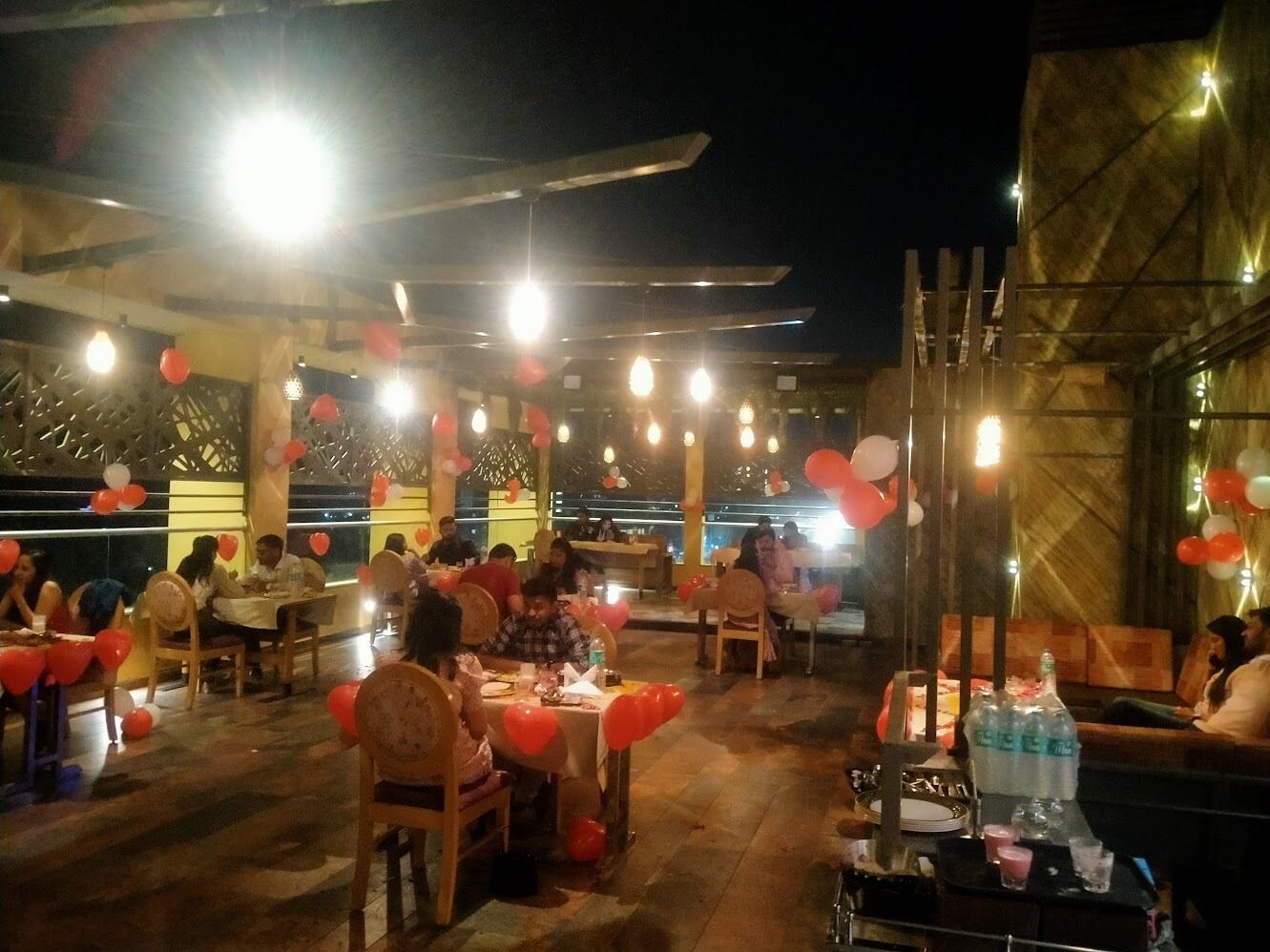 An outdoor dining area with tables and chairs, decorated with balloons.