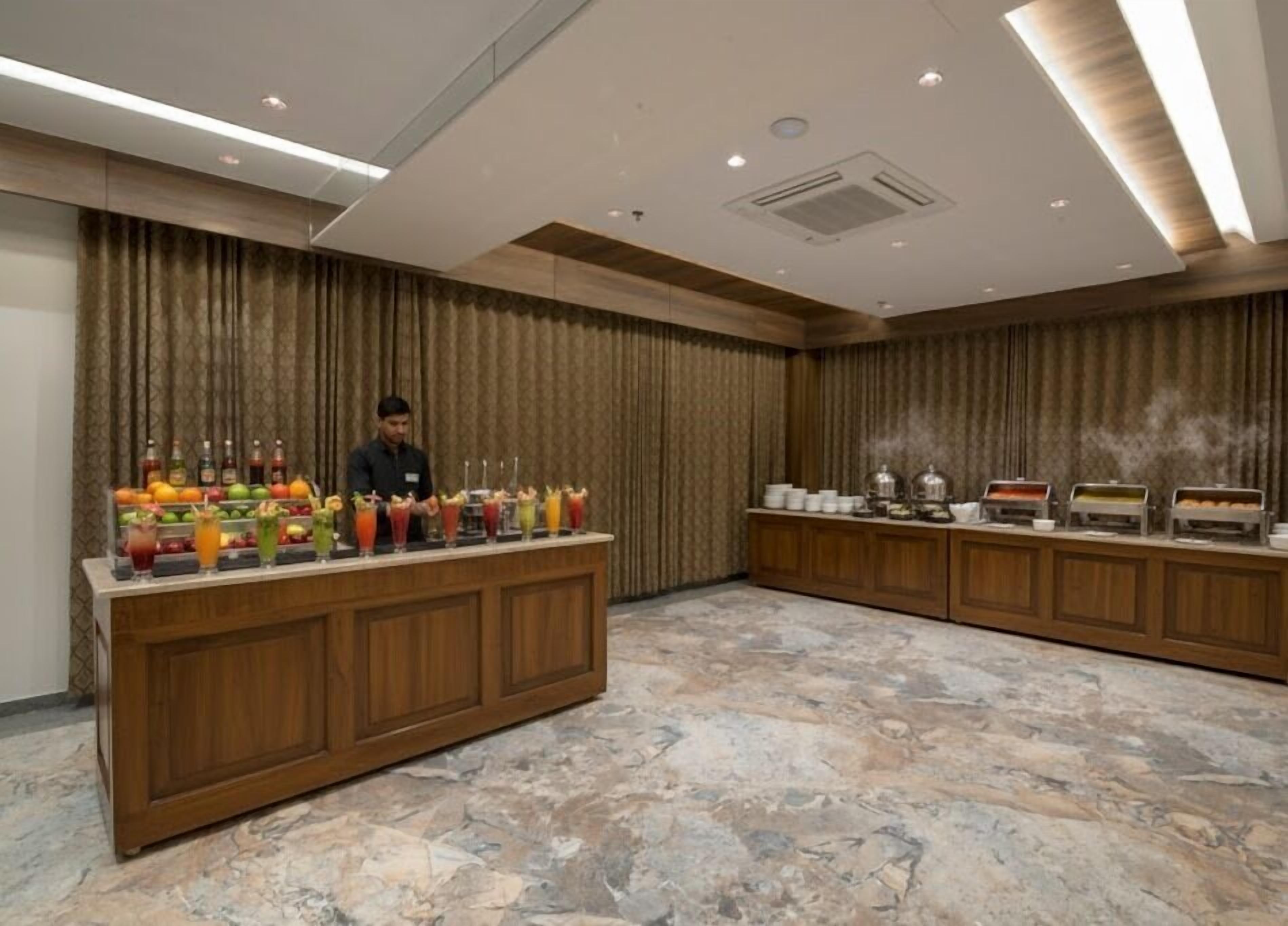 Un espace d’accueil d’hôtel doté d’un sol en marbre, d’un comptoir en bois avec un espace dédié aux boissons et d’un buffet.
