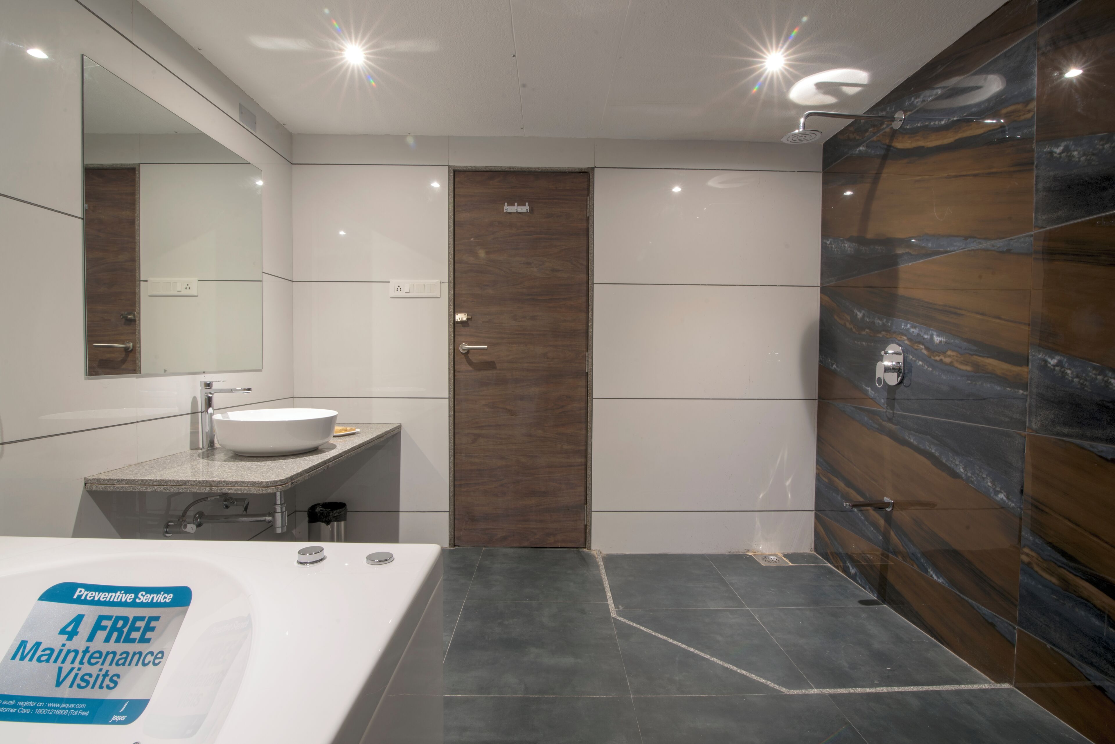 A modern bathroom with a large sink, mirror, and a shower area.