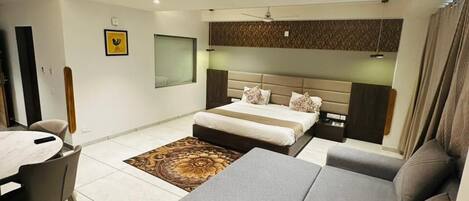 Un dormitorio moderno con cama, sofá y zona de comedor con mesa y sillas.