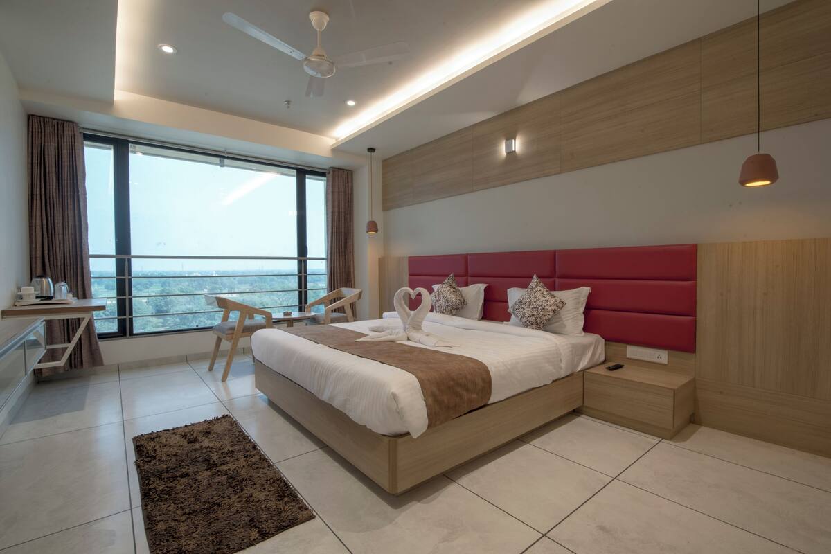 Ein modernes Schlafzimmer mit einem großen Bett, einem Schreibtisch und Blick auf die Stadt.