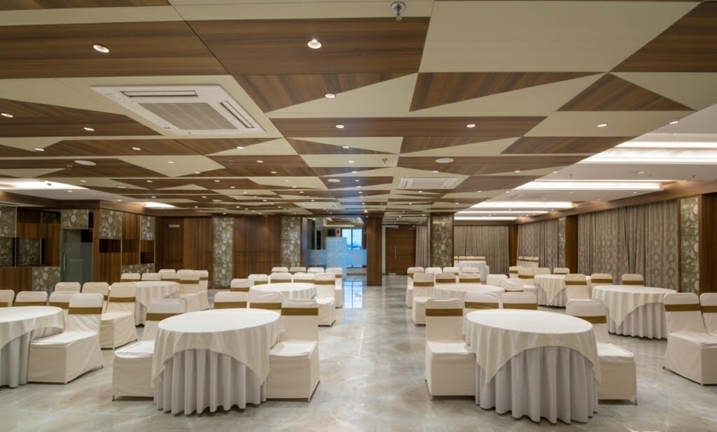 Une grande salle de banquet avec des tables rondes et des chaises, un plafond lambrissé et une allée centrale.