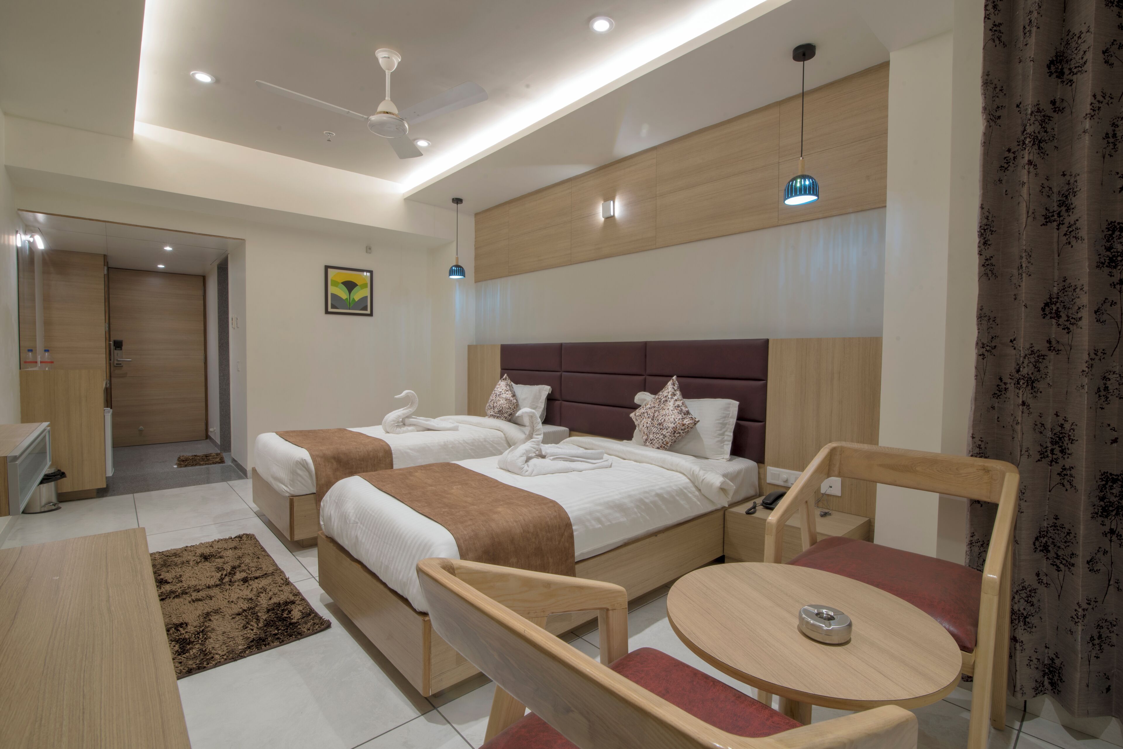 Una habitación de hotel moderna con dos camas, un escritorio, una silla y una mesita.