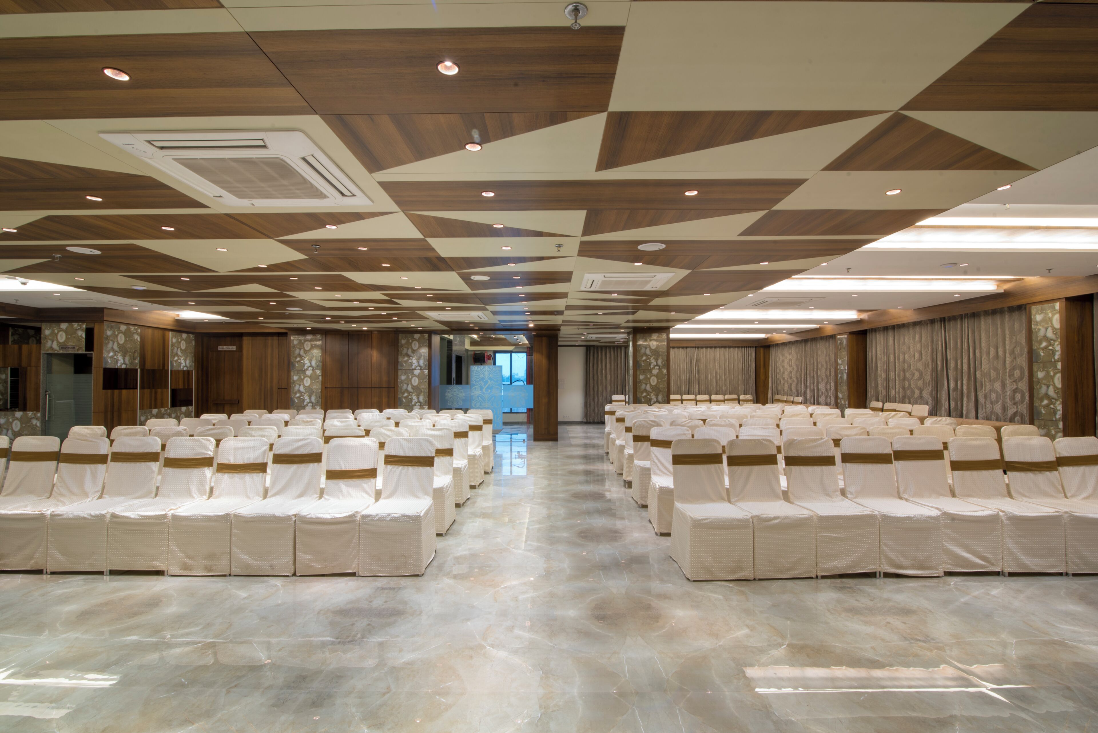 A conference room with rows of chairs, a polished floor, and a patterned ceiling.