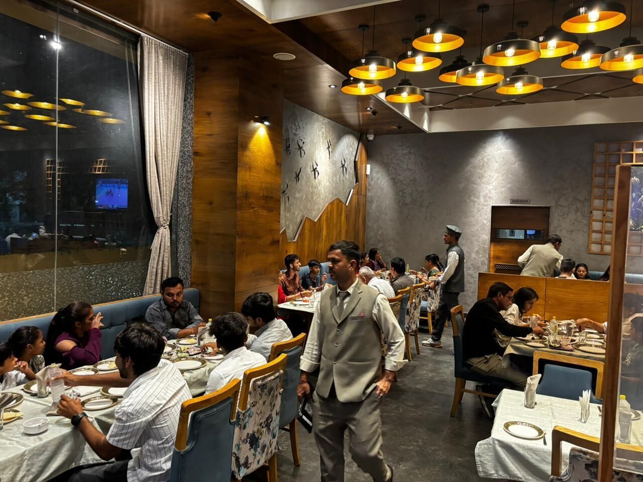 Ein Restaurant mit Holzwänden, mehreren Tischen und einem Kellner, der durch den Raum geht.