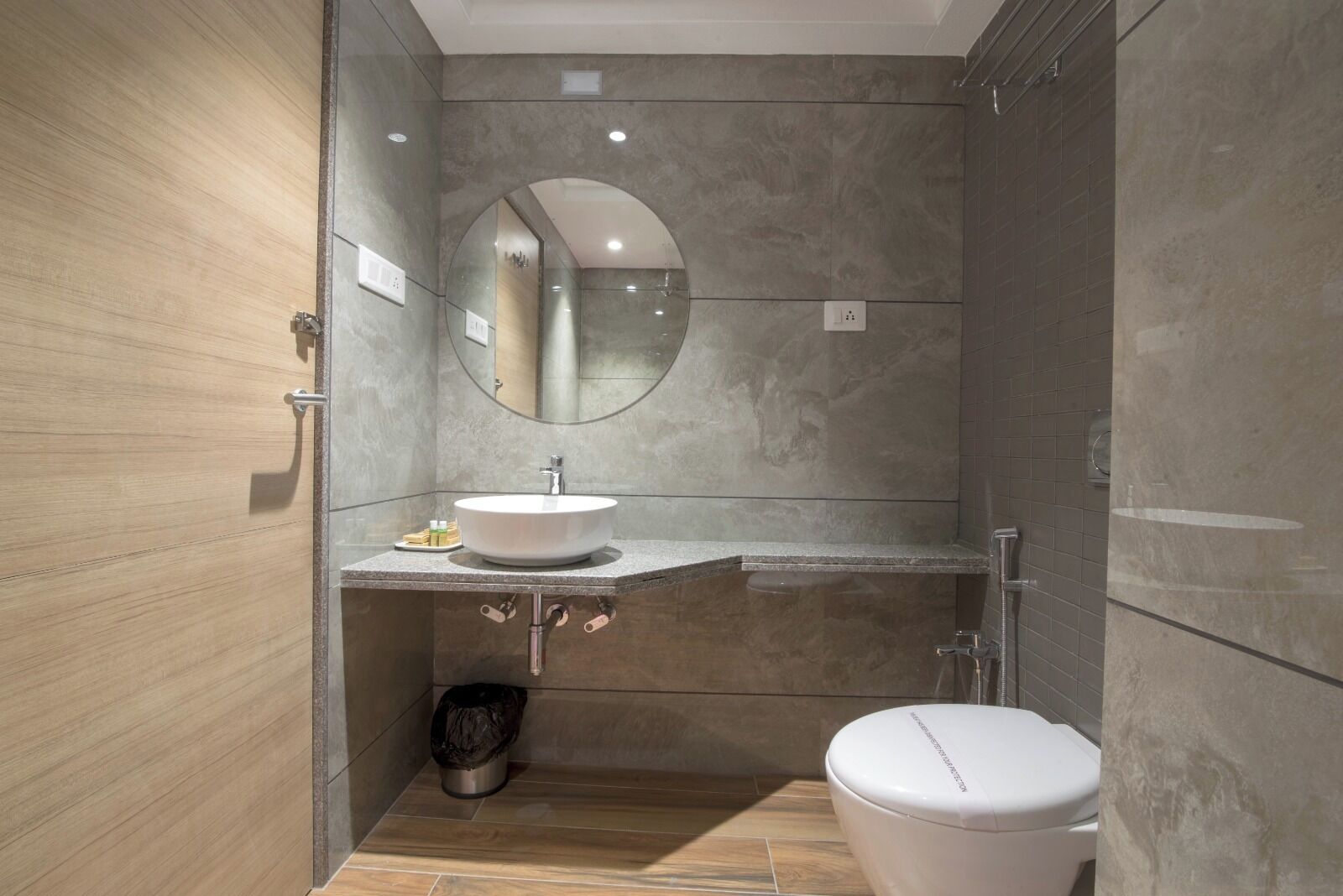 Een moderne badkamer met een ronde spiegel, een wastafel en een toilet.