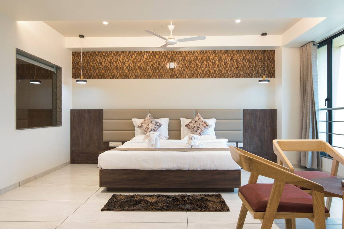 Ein modernes Schlafzimmer mit einem großen Bett, einem Deckenventilator und einem Holzsessel.