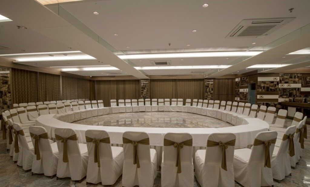 A circular conference room with white chairs and tables, arranged around a central table.