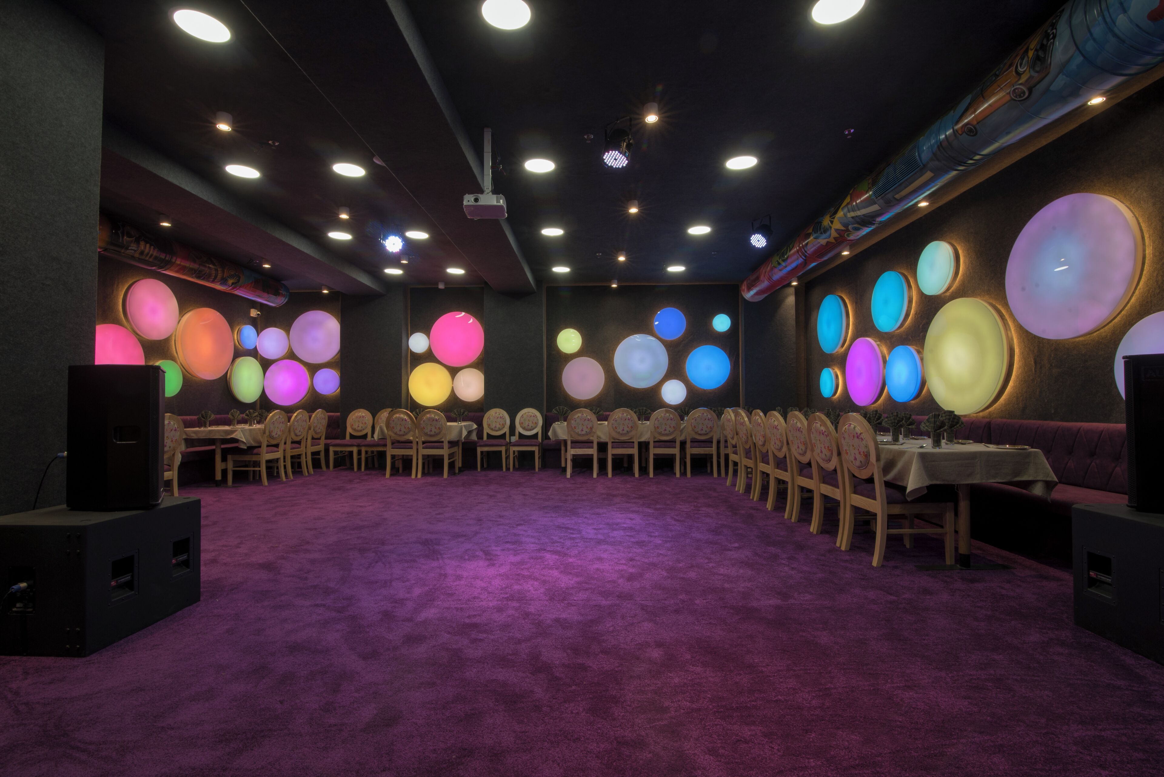 Un salón de conferencias con alfombra morada, mesas redondas y sillas.
