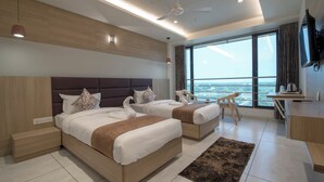 A modern hotel room with two beds, a desk, a chair, and a large window with a view. - Hotel Silvera Grand (Ahmedabad)