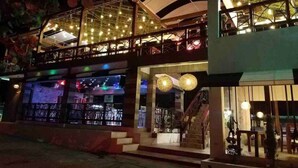 Un edificio de varios niveles con un restaurante en la planta baja, una zona de bar con luces de neón y una escalera que conduce a un nivel superior.
