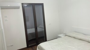 A bedroom with a bed, a wardrobe, and a bedside table. - SIKAN home By the sea (Butera)