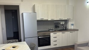 A modern kitchen with white cabinetry, a built-in oven, and a dining area with a table and chairs. - SIKAN home By the sea (Butera)