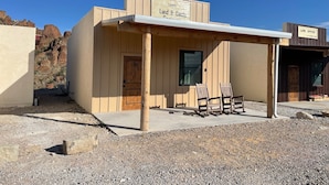 A small building with a wooden door labeled "19" and a sign above it reading "Lewis Land & Cattle". - Ten Bits Ranch - Room #19 Lewis Land & Cattle Co. (Terlingua)