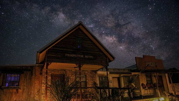 A rustic building labeled "Prospector Hotel" with a wooden facade and a stone base, under a starry night sky. - Ten Bits Ranch - Room # 20 - Law Office (Terlingua)