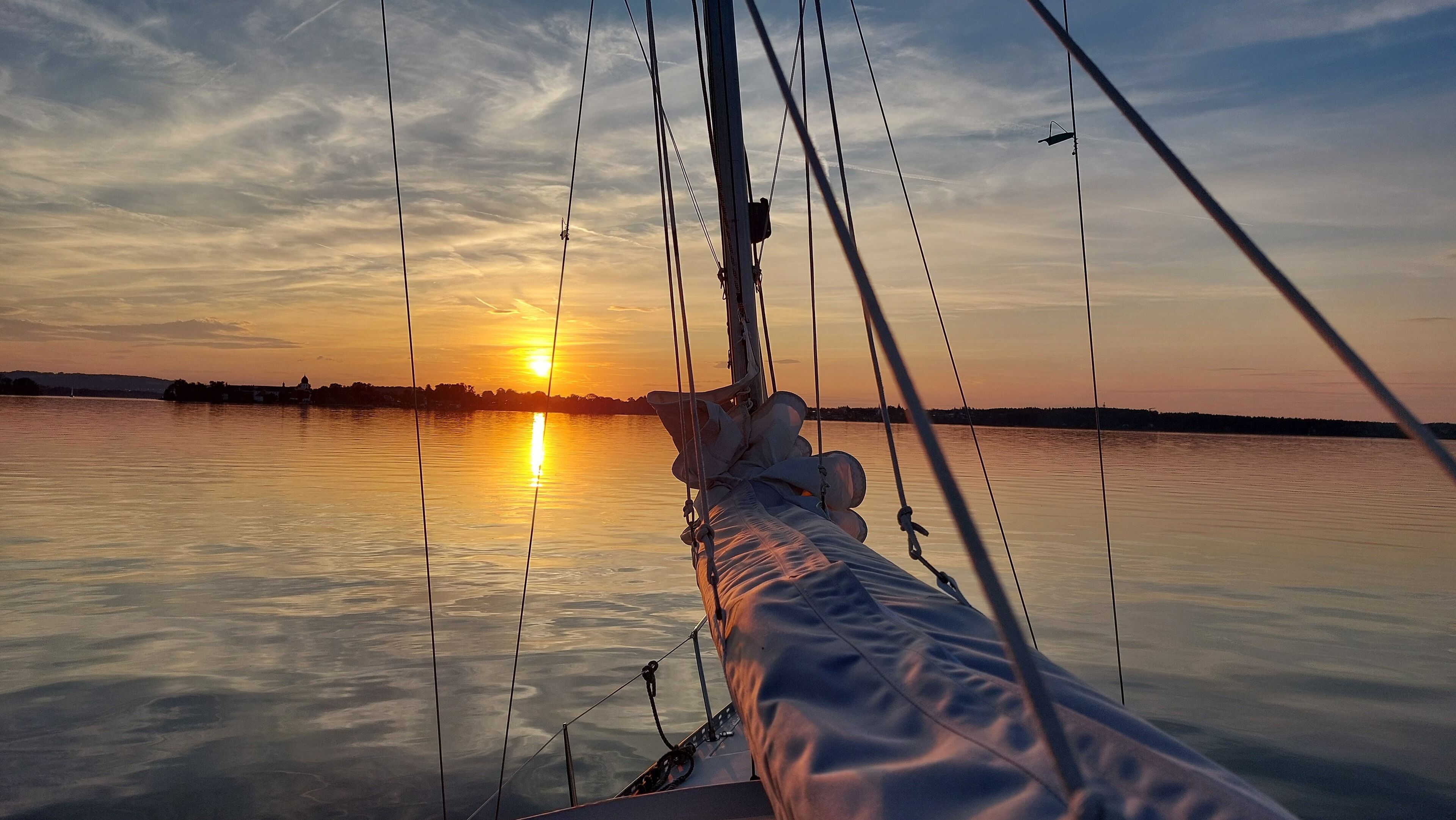A rope and rigging from a boat with a sunset over water.