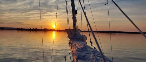 A rope and rigging from a boat with a sunset over water.