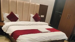 Ein ordentlich gemachtes Bett mit weißer und roter Bettwäsche, einem Holz-Kopfteil und einem gefliesten Boden.