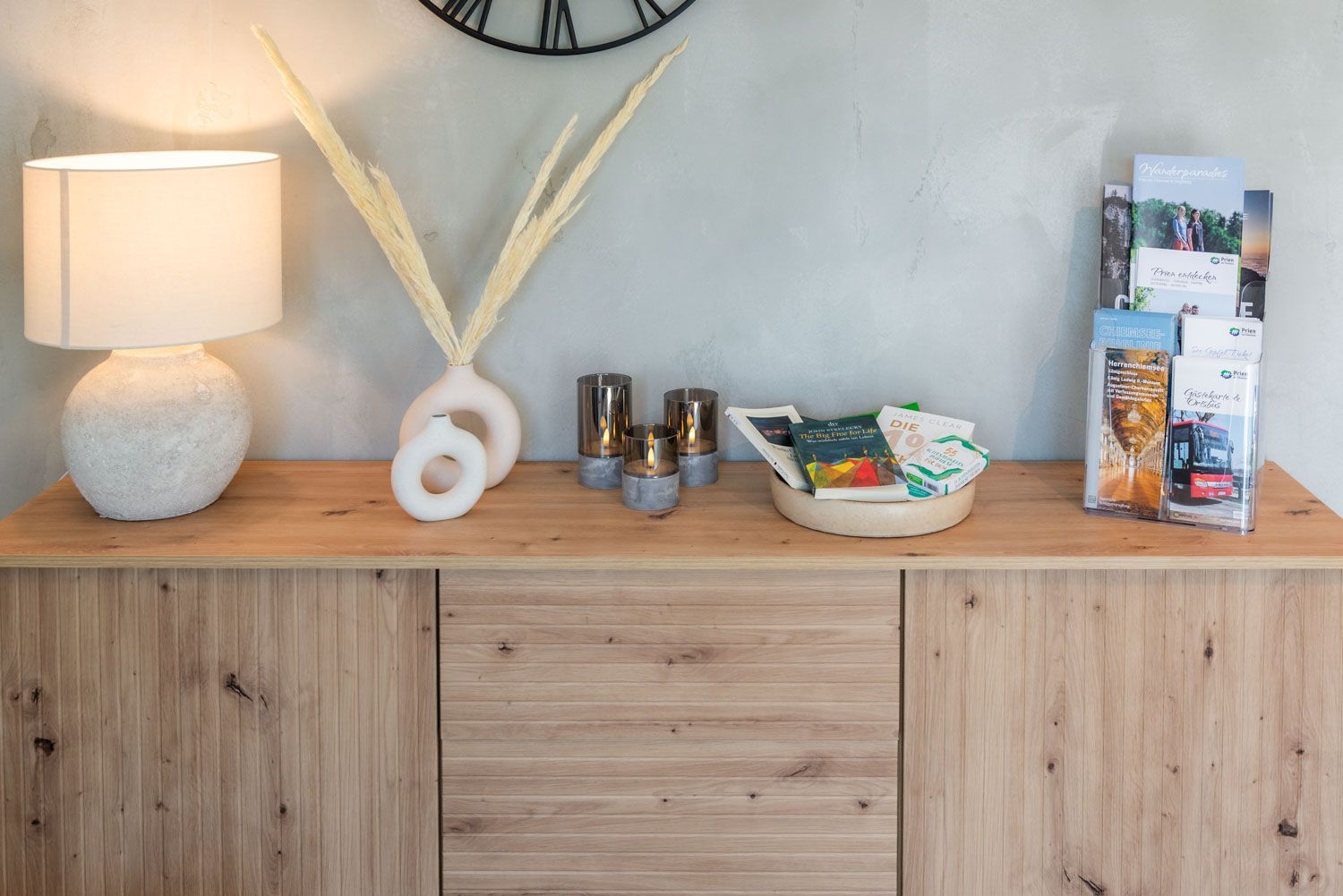 Un comptoir en bois agrémenté d’une lampe, d’objets décoratifs, de bougies et de brochures.