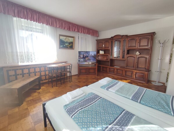 Una habitación con una cama, un escritorio, una silla, un armario de madera y un televisor.
