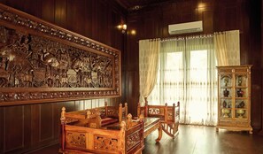 Une chambre traditionnelle avec un panneau mural en bois sculpté, un lit en bois aux motifs complexes et une armoire aux portes en verre.