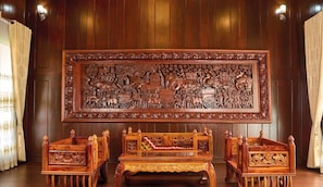 Une pièce traditionnelle en bois, avec un grand panneau sculpté, deux bancs en bois et un plancher en bois.