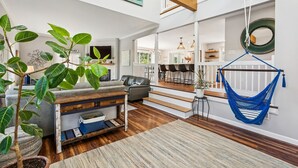 Zona d'estar àmplia amb una planta gran, un hamaca i una escala que condueix a un nivell superior.
