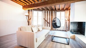 A modern living room with a wooden ceiling, a sofa, a hanging chair, and a fireplace. - Duplex "Le Bourgogne" historic center of Orléans (Orléans)