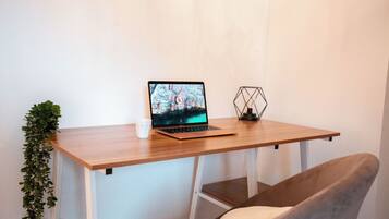 Een houten bureau met een laptop, een witte mok en een decoratief object met een geometrisch patroon.