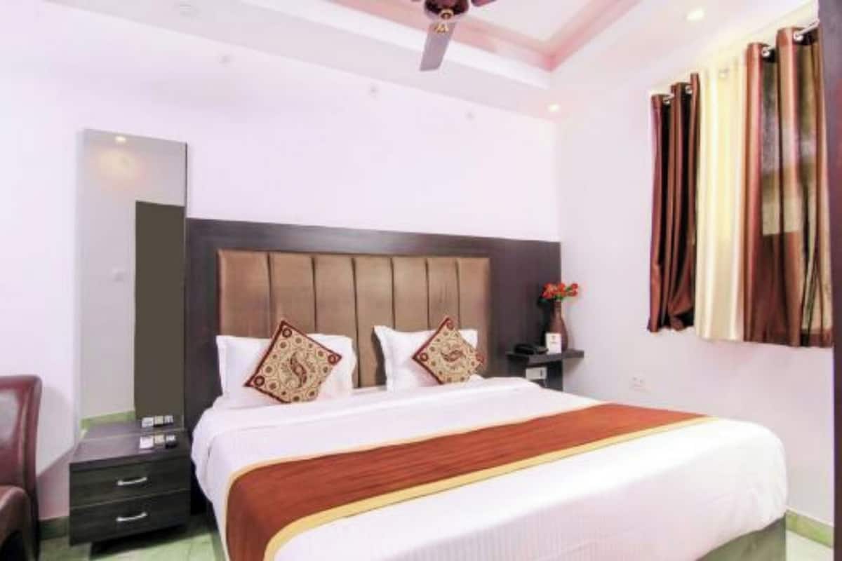 A hotel room with a large bed, a nightstand, a chair, a ceiling fan, and a mirror.