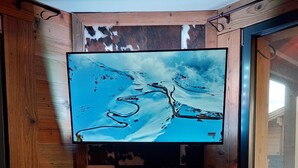 Puinen mökki, jonka sisätiloissa on televisio asennettuna takan yläpuolelle.