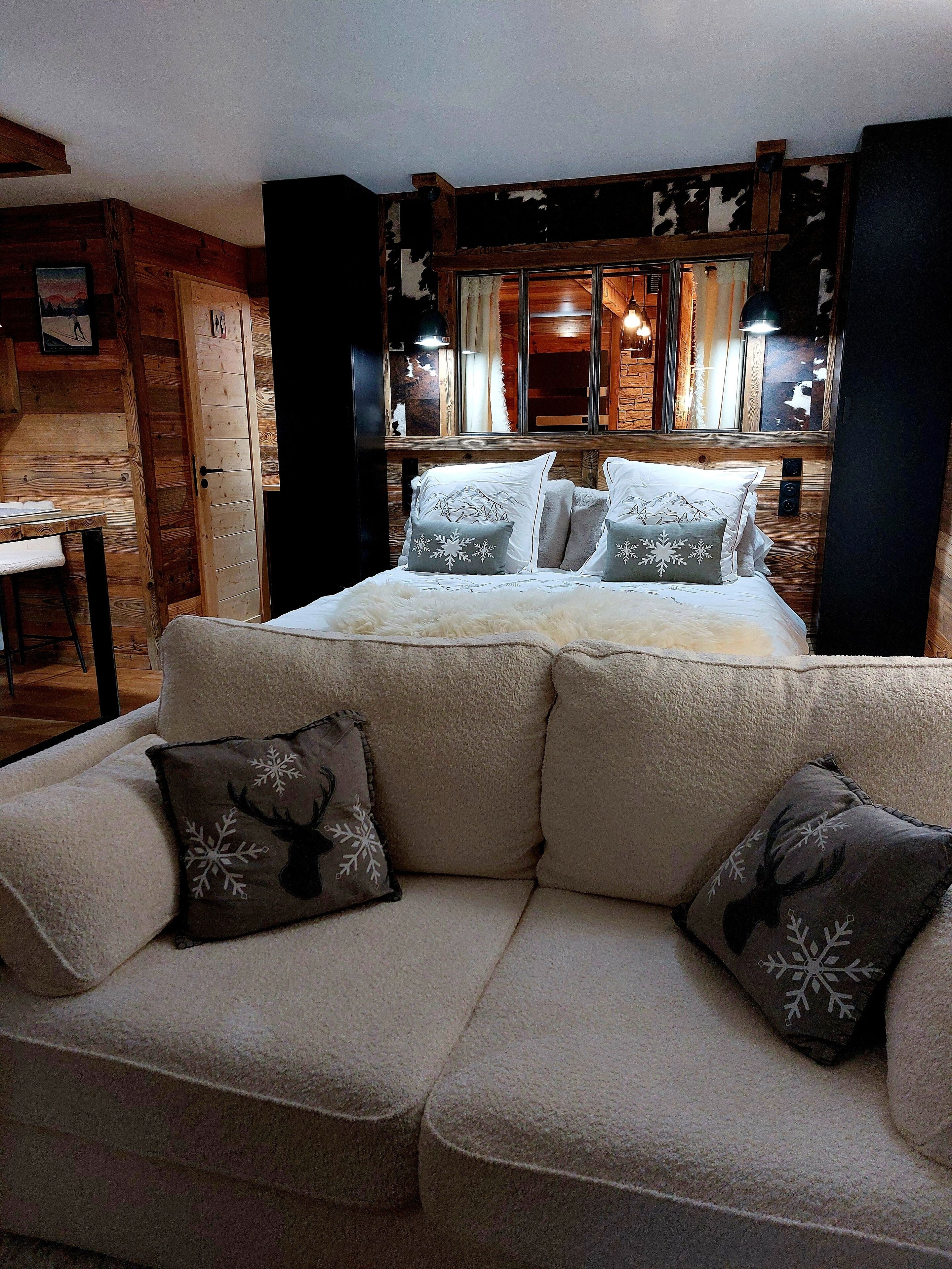 A cozy room with a bed, a sofa, and a wooden wall.