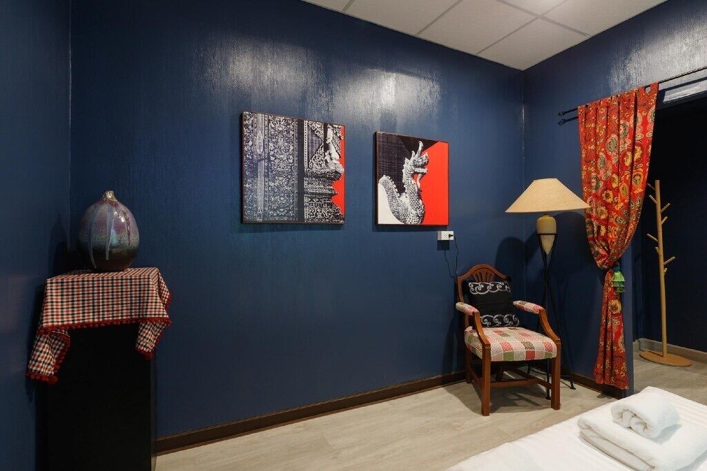 A room with dark blue walls, a wooden chair with a checkered cushion, a table with a checkered cloth, and two artworks.