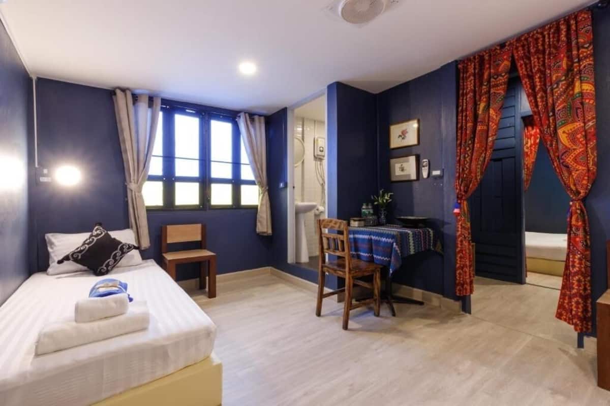 A bedroom with a bed, a desk, and a chair.