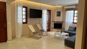 A living room with a fireplace, a sofa, a coffee table, and a TV mounted on the wall.
