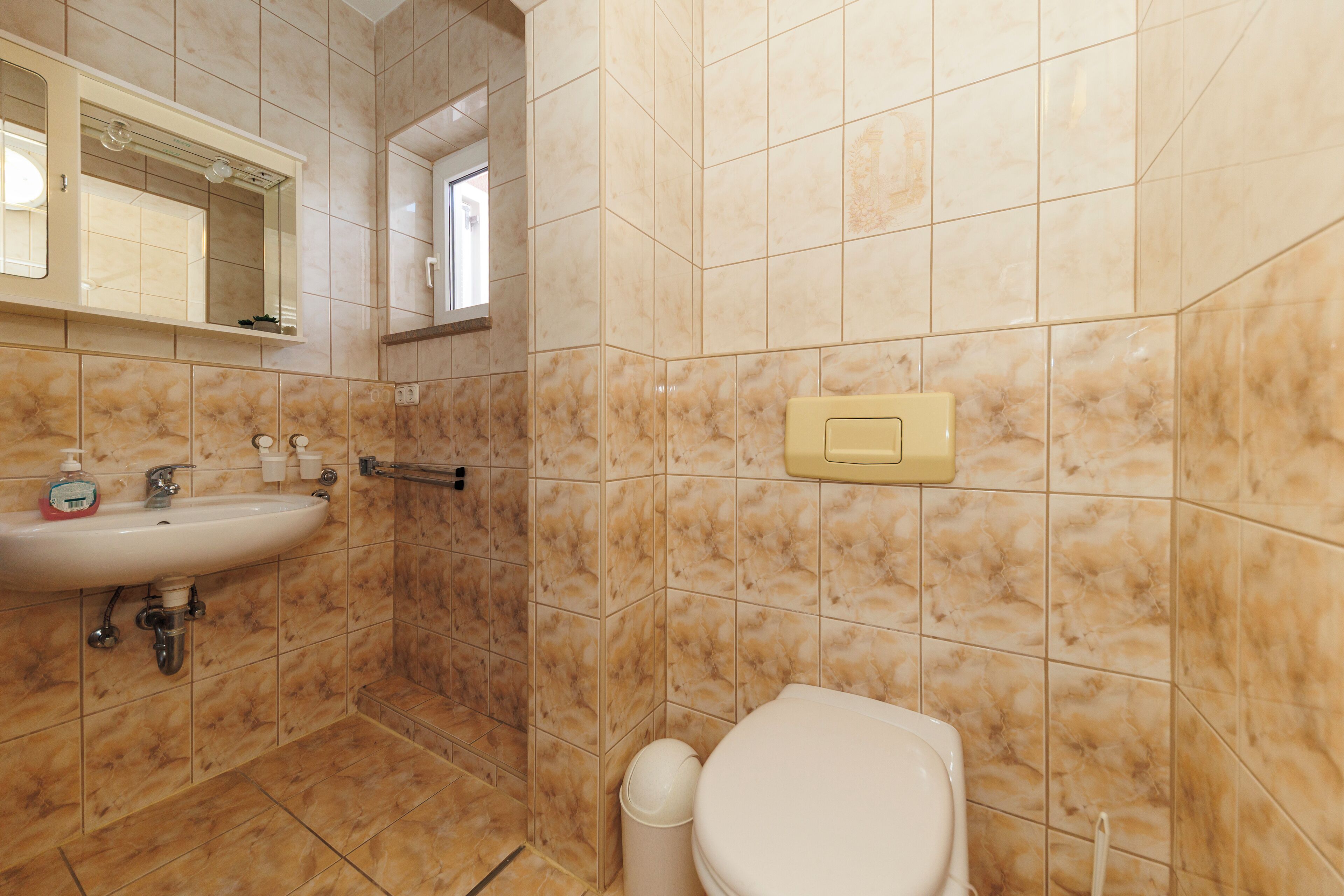 A bathroom with a sink, mirror, toilet, and a towel rack.