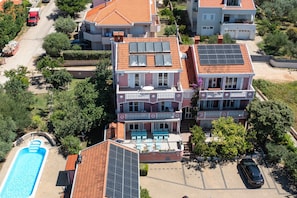A multi-story residential building with a rooftop pool, solar panels, and a covered patio area.